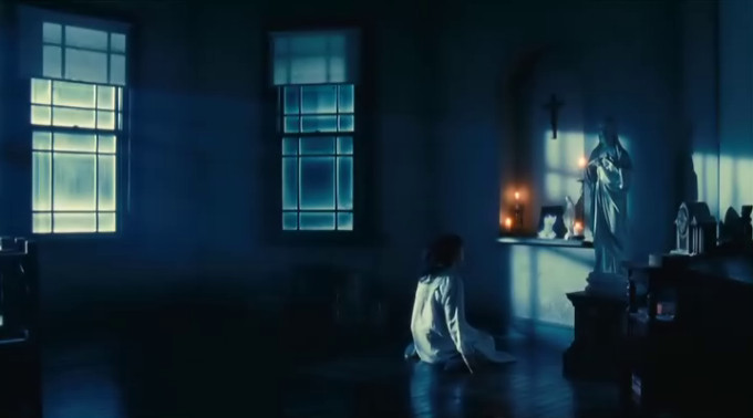 Screen capture from Fatal Frame showing a girl in her nightie sitting on the floor in a creepy moonlit room while staring at a candlelit altar with a photo of another girl upon it