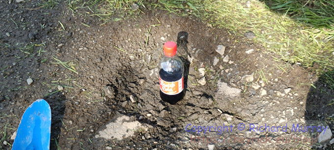 A small bottle of coke sitting in a pothole